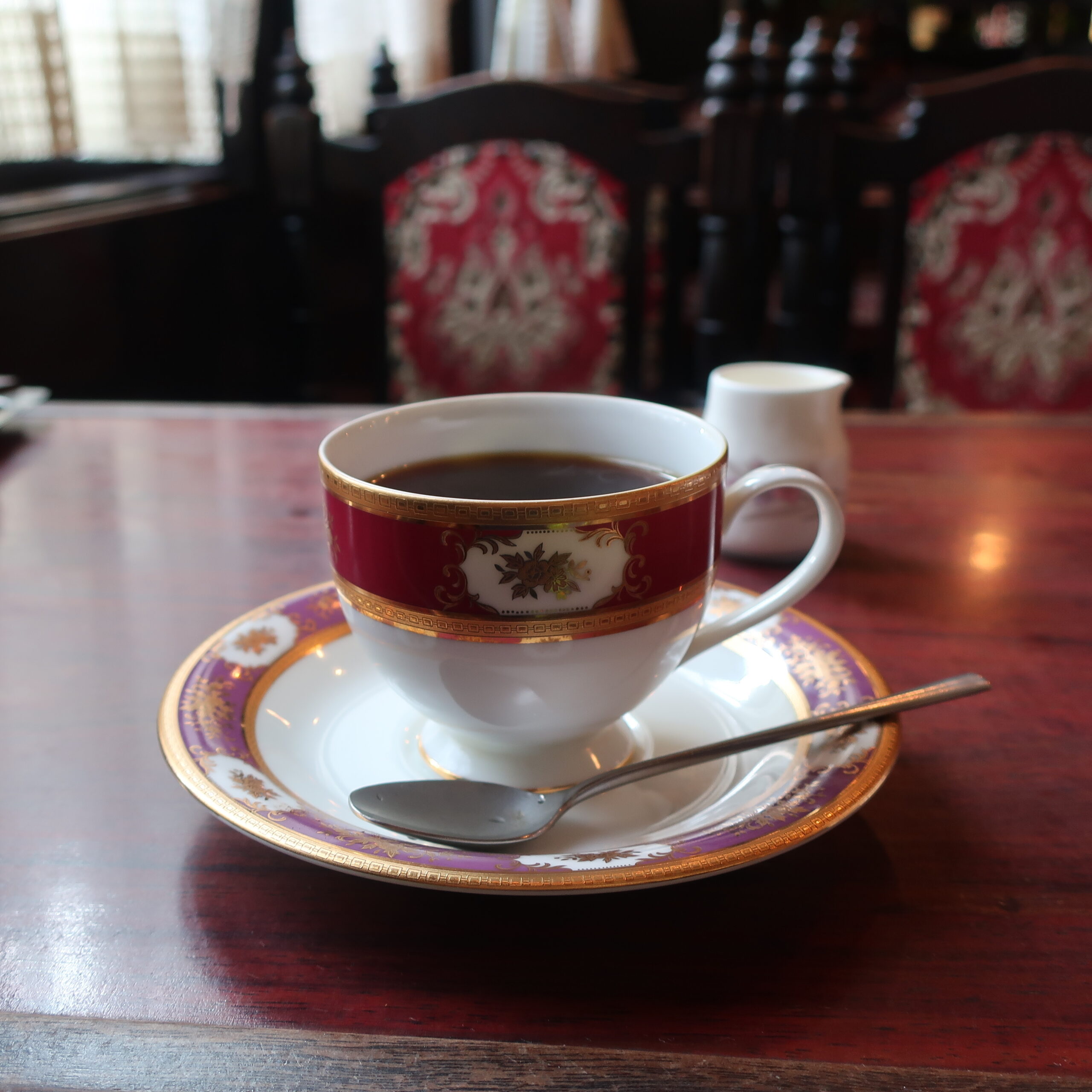 KAN-KOBE-02 · a coffee cup on an old wooden counter — 1:1, 900×900