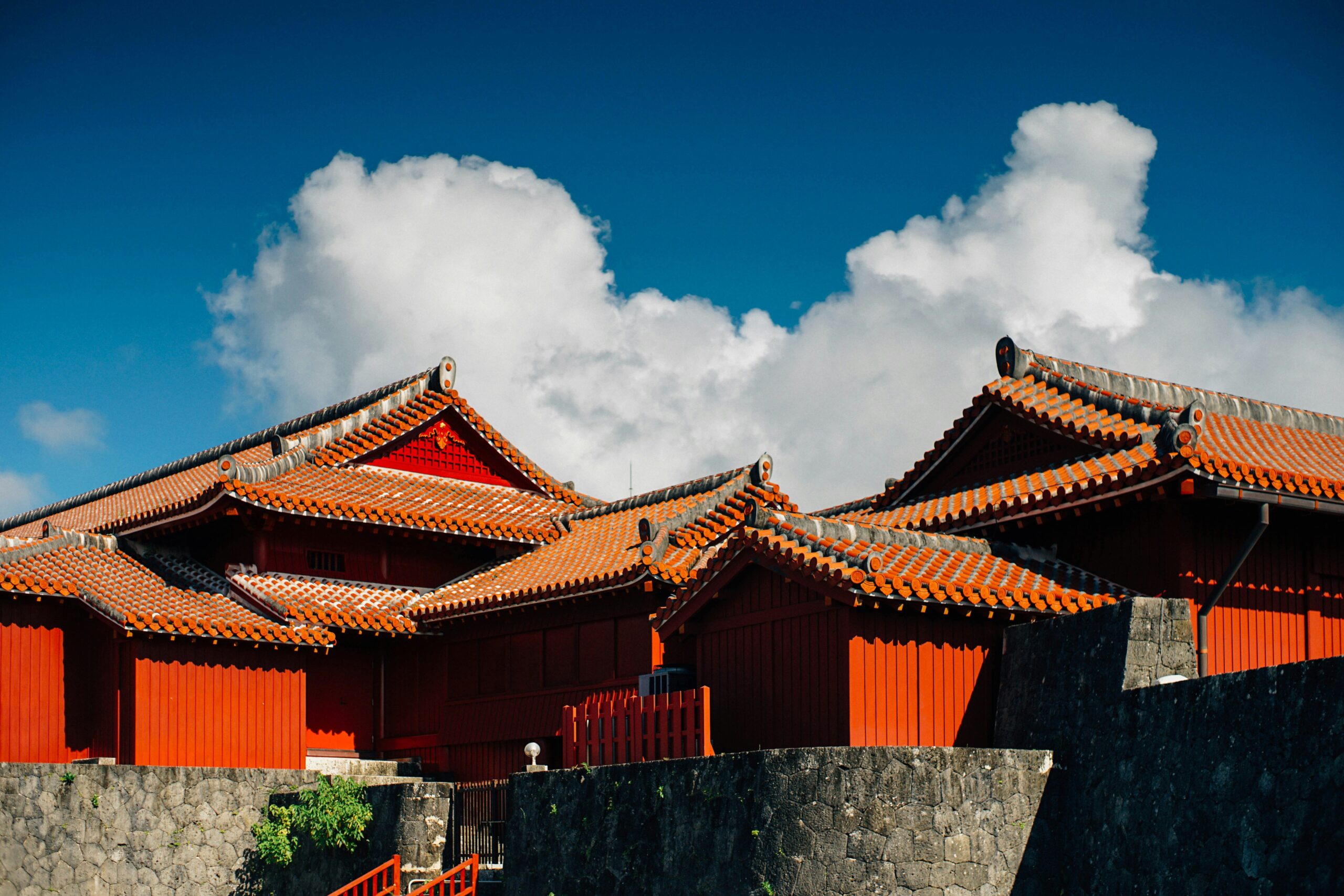 OKI-CULTURE-01 · Ryukyu heritage — a red tile settlement, castle stonework, or a pottery workshop shelf. No costumes or staged performance. 3:2, 1800×1200