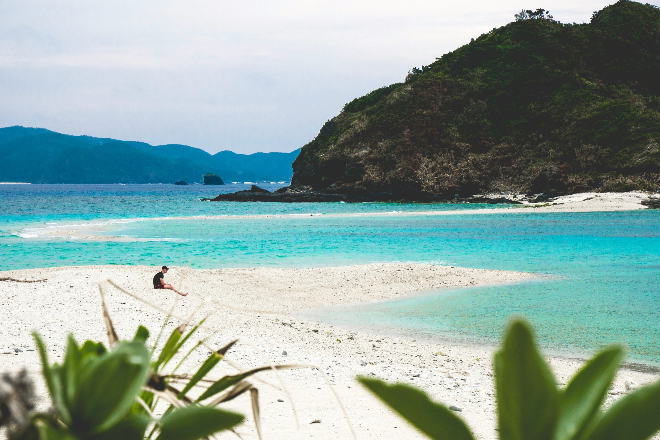 OKI-ISLAND-01 · a smaller island — a village lane, a ferry deck, or an empty shore on Kerama. Quiet and lived-in. 3:2, 1800×1200