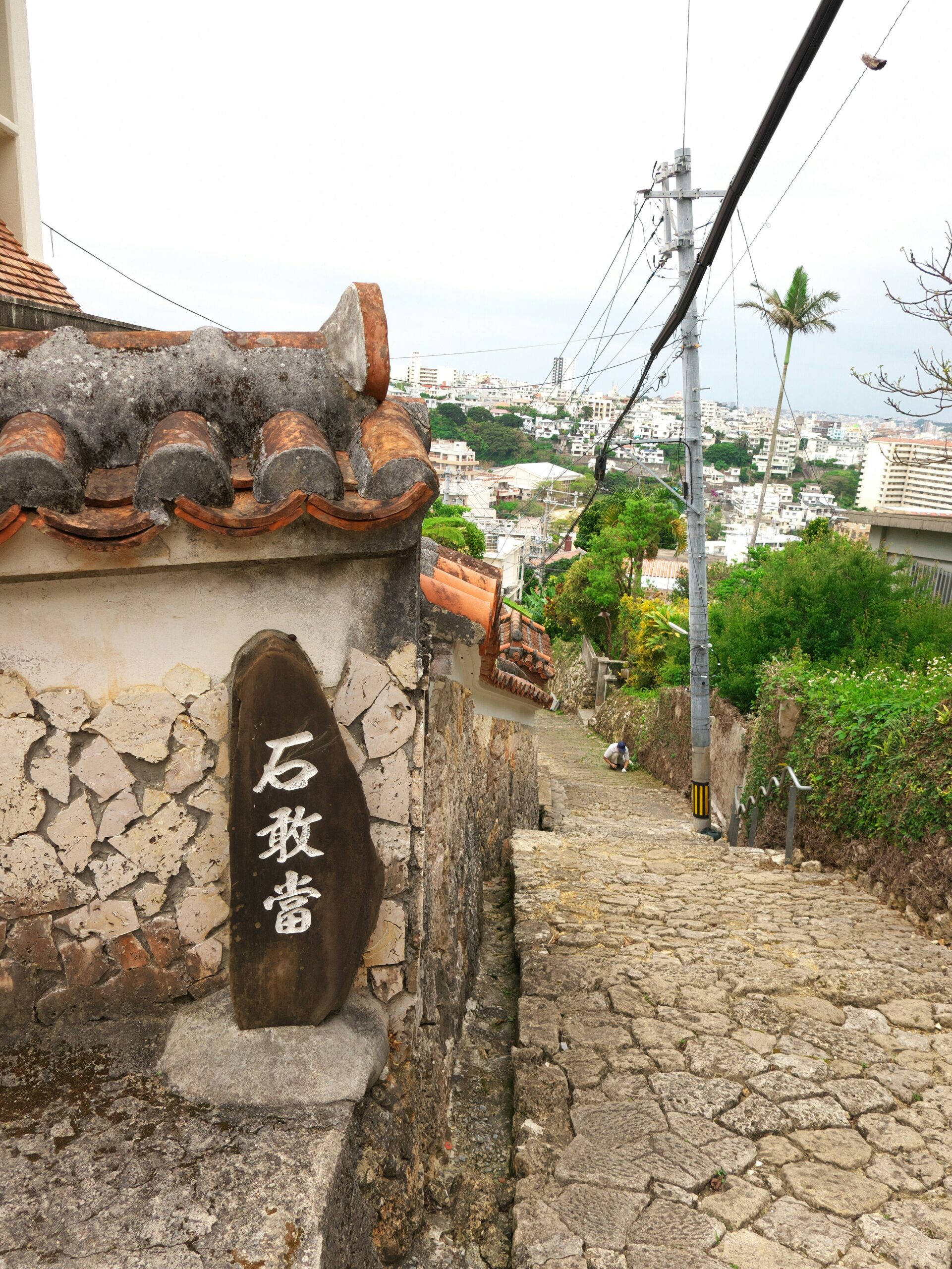 OKI-RYUKYU-01 · red tile village or traditional architecture — stone walls, tiled roofs, lived-in streets. 3:4, 1200×1600