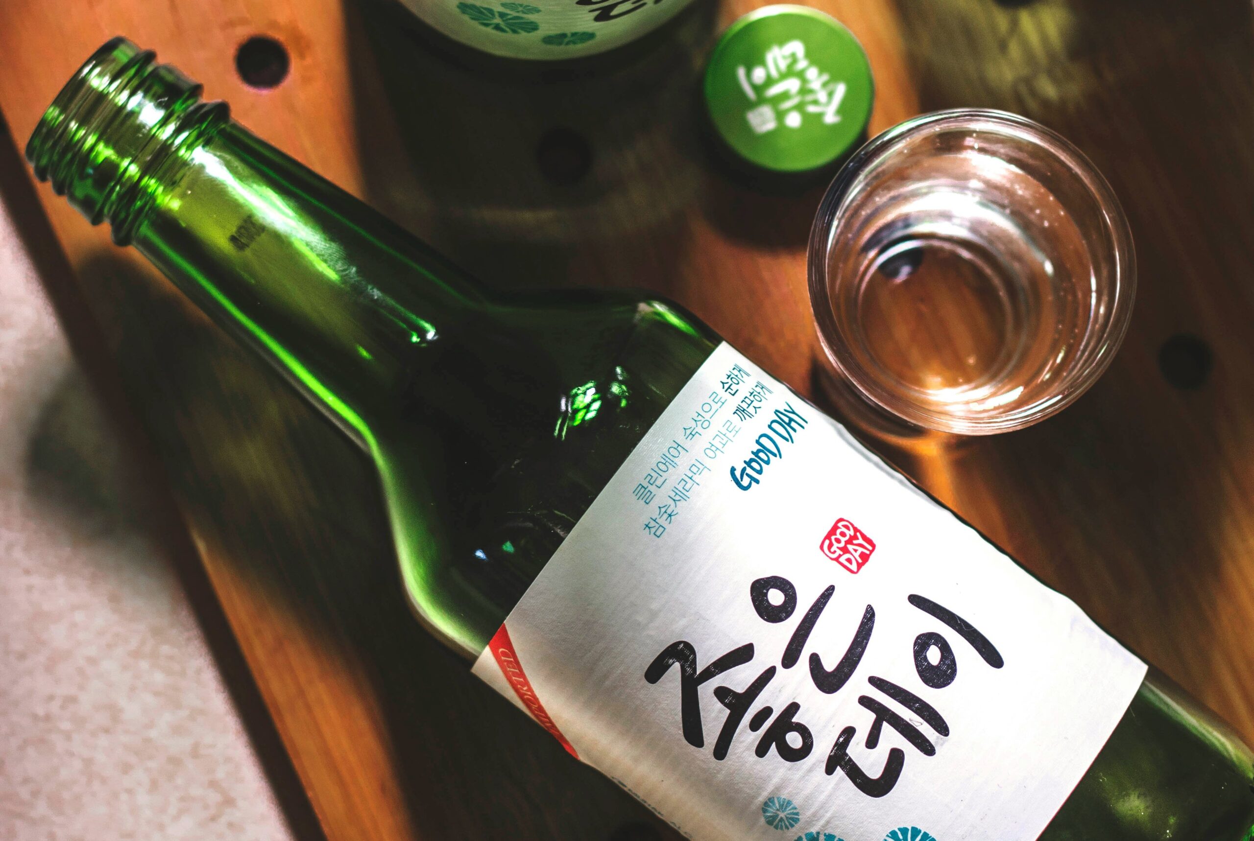 BS-EAT-05 · late-night drinking table — bottles, grilled food, warm light on faces. 3:2, 1500×1000